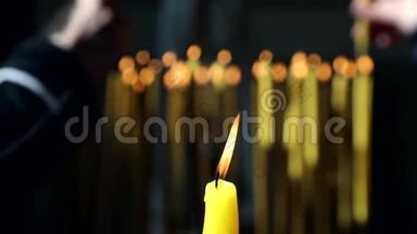 在教堂里点燃的一支黄色蜡烛和背景中点燃的几支蜡烛点燃了基督徒，并点燃了他们